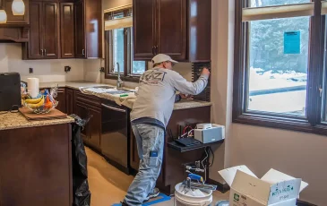 A Kaz craftsman working on tiling the backsplash of a new kitchen renovation