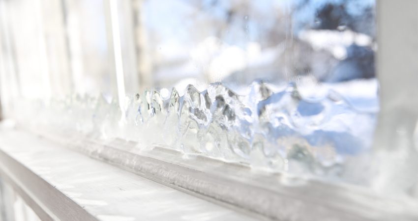Ice forming on the inside glass of a drafty window in winter