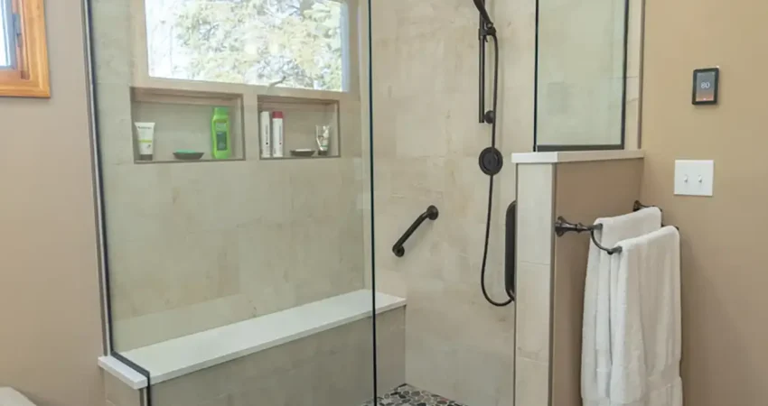 Custom glass walk-in shower with river rock pebble tile floor and matte black fixtures installed by Kaz Home Improvements in Orchard Park near Buffalo, Western New York.