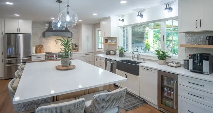Modern kitchen remodel featuring a large white quartz island, black farmhouse sink, and custom white cabinetry by Kaz Home Improvements in Buffalo, Western New York