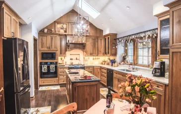 An open layout kitchen with a vaulted ceiling and beautifully built and stained custom cabinets