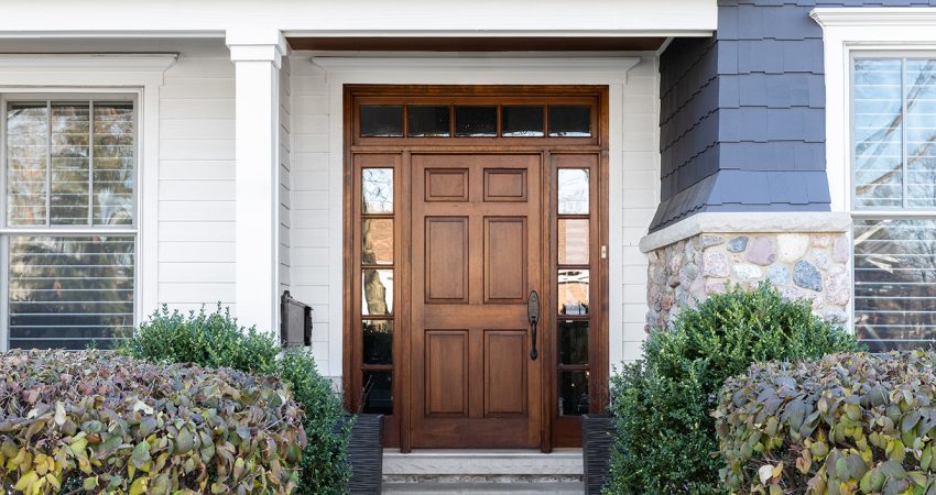 A wooden front door, surrounded by windows, with white, blue