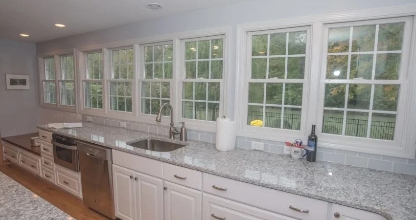 Kitchen remodel featuring custom white cabinets, granite countertops, and large grid windows installed by Kaz Home Improvements in Buffalo, Western New York.