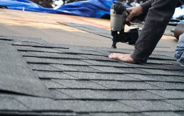 handyman using nail gun to install shingle to repair roof