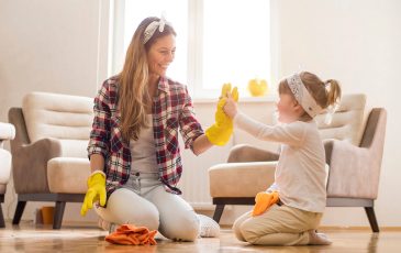 Daughter and mother cleaning home together and having fun.