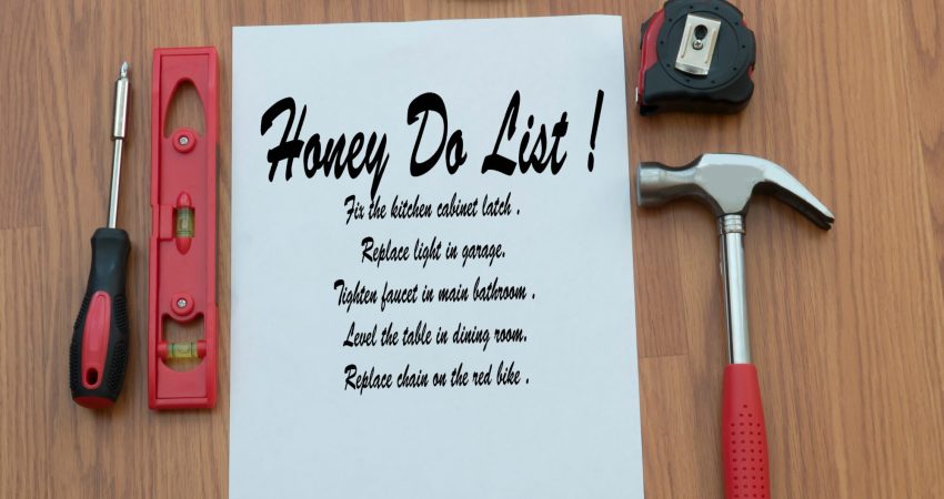 A to-do list on a table with varius tools–including a hammer, scre driver, tape measure and pliers