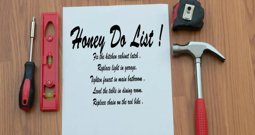 A to-do list on a table with varius tools–including a hammer, scre driver, tape measure and pliers