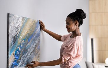 Picture of a woman hanging a painting on a wall