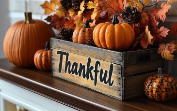 A wooden crate with the word "thankful" printed on the side, filled with pumpkins